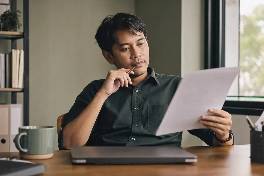 A recruiter at his desk weighing a decision over a printed scorecard