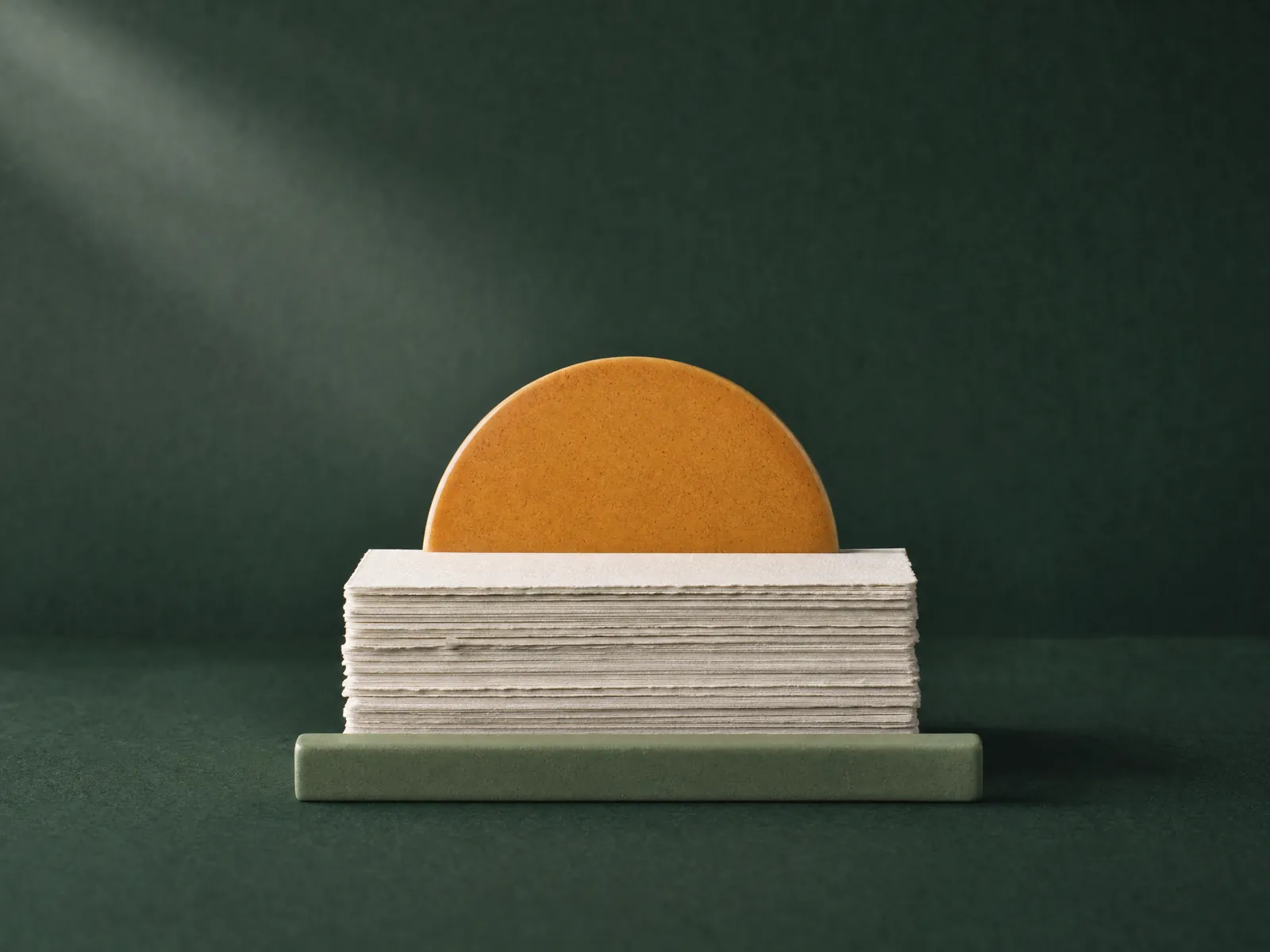 An amber ceramic sunrise rising behind a stack of handmade paper cards